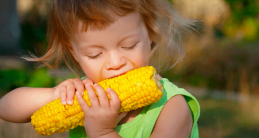 Girl-Taking-a-Bite-of-Corn-1024x600.png